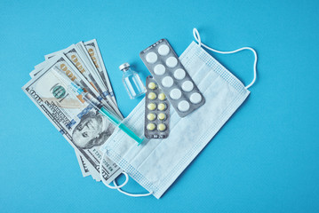 Pills, protective mask and dollar bills on blue background. Expensive medicine concept. Pharmaceutical industry and medical insurance