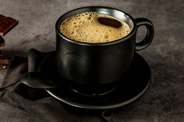 Black coffee cup with coffee on a dark background. With copy space for your text. Cup of coffee on a black background low key copy space.