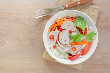 top view  of spicy vietnamese pork sausage salad in a ceramic bowl on wooden table. delicious asian style food menu.