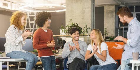 Young creative team cheering new comer girl in office