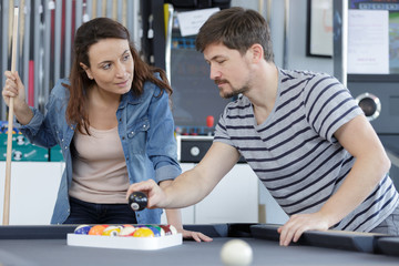 couple setting up the balls on a billiards table