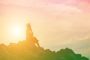 silhouette of woman praying over beautiful sky background
