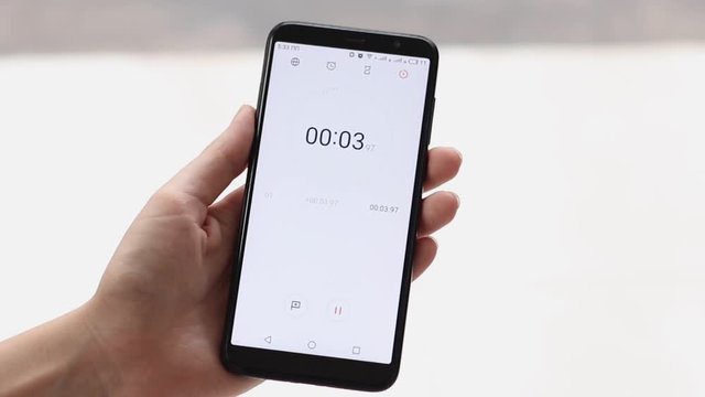 The stopwatch in the hands of a woman counts to 10 and the girl stops him