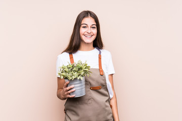 Young gardener caucasian woman holding a plant isolatedhappy, smiling and cheerful.