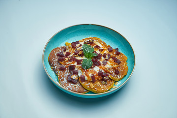 Appetizing pancakes with jam, sour cream and pumpkin in a blue plate isolated on grey background. Tasty breakfast food