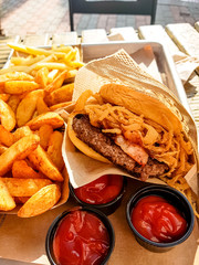 Burgers, potatoes, ketchup and mugs of beer on the table of a street cafe.