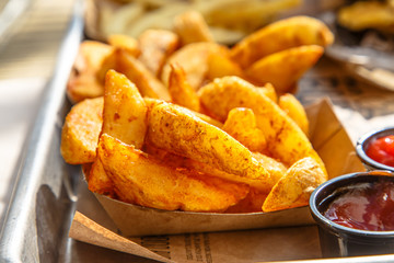 Burgers, potatoes, ketchup and mugs of beer on the table of a street cafe.