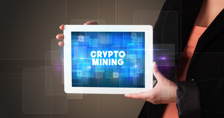 Young business person working on tablet and shows the inscription: CRYPTO MINING