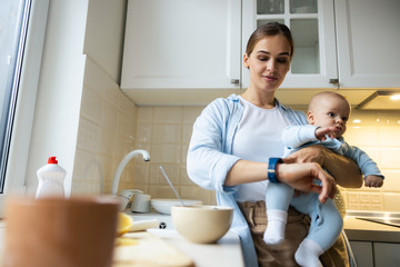 Smiling beautiful mom holding baby and checking the time
