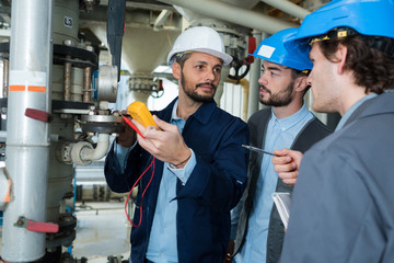 industrial engineer holding voltmeter inspecting pipe gauge