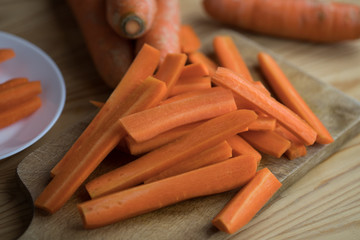 Carrots cut into strips on a wooden board. Closeup view. Preparation of healthy fries