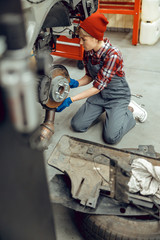 Young woman in overalls checking brake rotors
