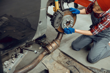 Young auto mechanic checking the braking system