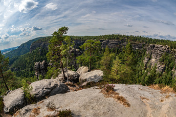 Pravcicka brana in Bohemian Switzerland. Prebischtor Gate mountain view. Narrow rock, largest natural sandstone arch in Europe. Hill scenery with greenery, blue sky and sunlight, natural environment.