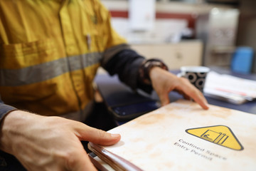 Safety workplace construction worker holding confined space permit book prior starting job  - obrazy, fototapety, plakaty