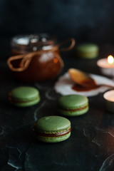 Macaroons. Delicious french dessert. Romantic composition with a jar of caramel and candles