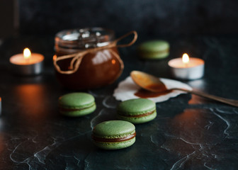Macaroons. Delicious french dessert. Romantic composition with a jar of caramel and candles