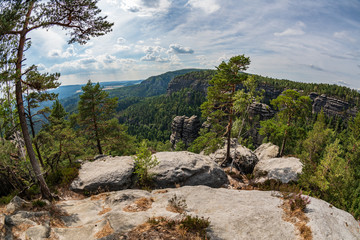 Pravcicka brana in Bohemian Switzerland. Prebischtor Gate mountain view. Narrow rock, largest natural sandstone arch in Europe. Hill scenery with greenery, blue sky and sunlight, natural environment.