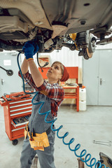 Woman repairing the underbody of a car