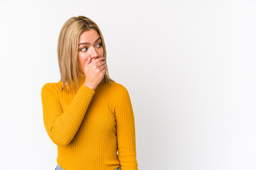 Young blonde caucasian woman isolated thoughtful looking to a copy space covering mouth with hand.