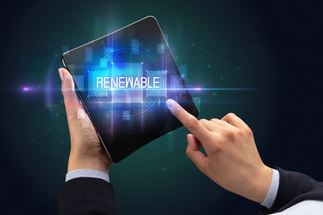 Businessman holding a foldable smartphone with RENEWABLE inscription, new technology concept