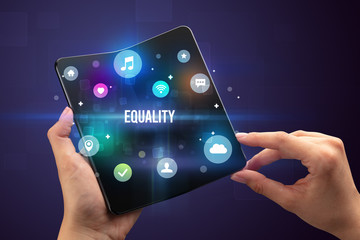 Businessman holding a foldable smartphone with EQUALITY inscription, social media concept