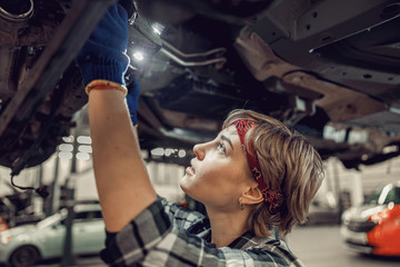 Young female gazing at a lifted auto - obrazy, fototapety, plakaty