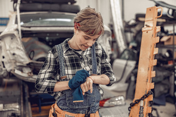 Girl in overalls standing in a car workshop