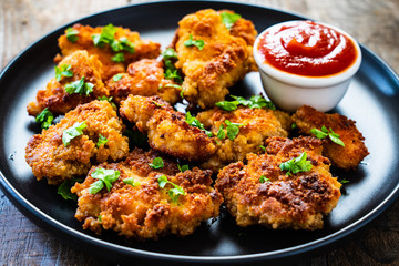 Fried chicken nuggets with ketchup on wooden table