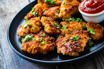 Fried chicken nuggets with ketchup on wooden table
