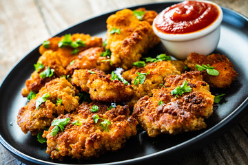 Fried chicken nuggets with ketchup on wooden table
