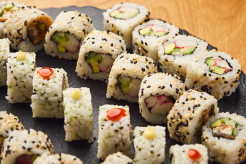 Various kinds of sushi roll set served on black stone. Japanese food