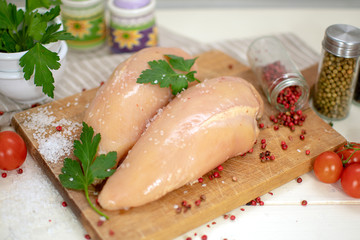 Raw chicken breast with cherry tomatoes and parsley on wood cuttingboard. Preparation for cooking raw chicken fillet.