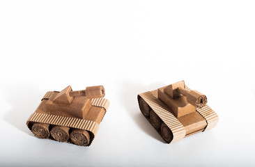 two toy tanks made by children from corrugated cardboard are fighting. toy cardboard tanks isolated on a white background. February 23. Men's day