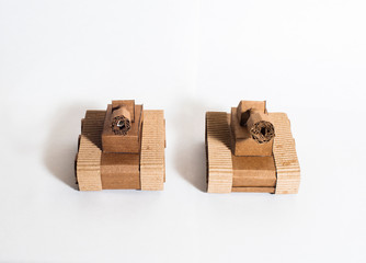 two toy tanks made by children from corrugated cardboard are fighting. toy cardboard tanks isolated on a white background. February 23. Men's day