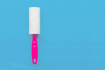 Glue roller for cleaning clothes from wool and animal hair on a blue background with a place for writing.