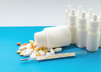 A jar of pills, a thermometer and Nosal drops on a blue background. Concept of health protection.