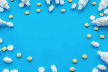 Bottles with nose drops and pills on a blue background with a place for writing. The view from the top.