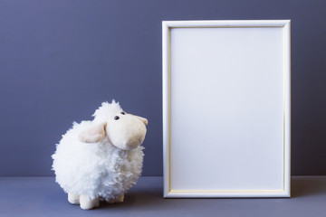white photo frame and soft toy on a gray background copy space