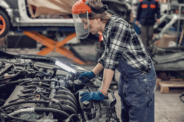Experienced female mechanic checking a car engine