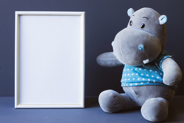 white photo frame and soft toy on a gray background copy space