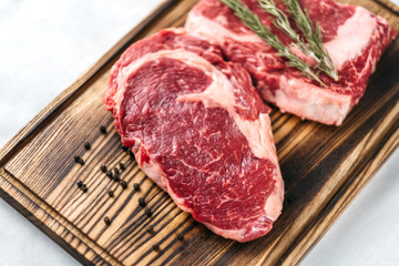 Raw meat beef steak, with ingredients for cooking on a wooden board and white background. Top view