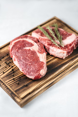 Raw meat beef steak, with ingredients for cooking on a wooden board and white background. Top view