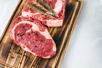 Raw meat beef steak, with ingredients for cooking on a wooden board and white background. Top view