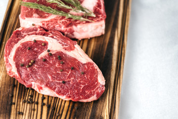 Raw meat beef steak, with ingredients for cooking on a wooden board and white background. Top view