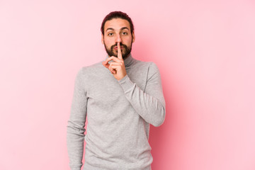 Young long hair man isolated on a pink background keeping a secret or asking for silence.