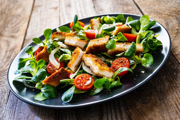 Fried chicken breast and vegetables on wooden table