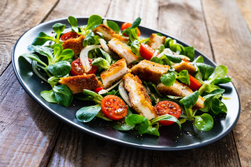 Fried chicken breast and vegetables on wooden table