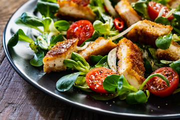 Fried chicken breast and vegetables on wooden table