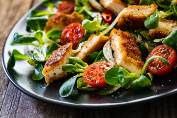 Fried chicken breast and vegetables on wooden table
